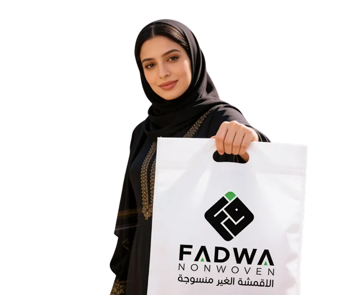 A woman in an elegant black hijab holding up a premium white non-woven handle bag (D-cut style) featuring the black and green Fadwa Non Woven corporate logo printed prominently on the front.